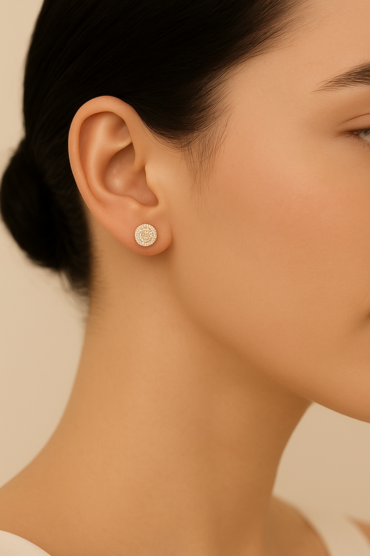 Close-up of a woman wearing a small round earring against a beige background