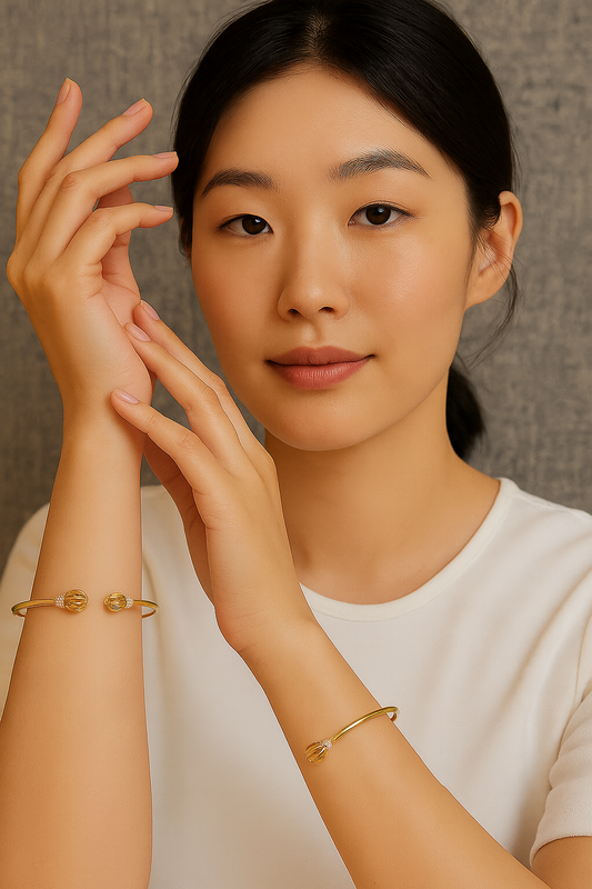 Woman wearing gold bracelets on a neutral background