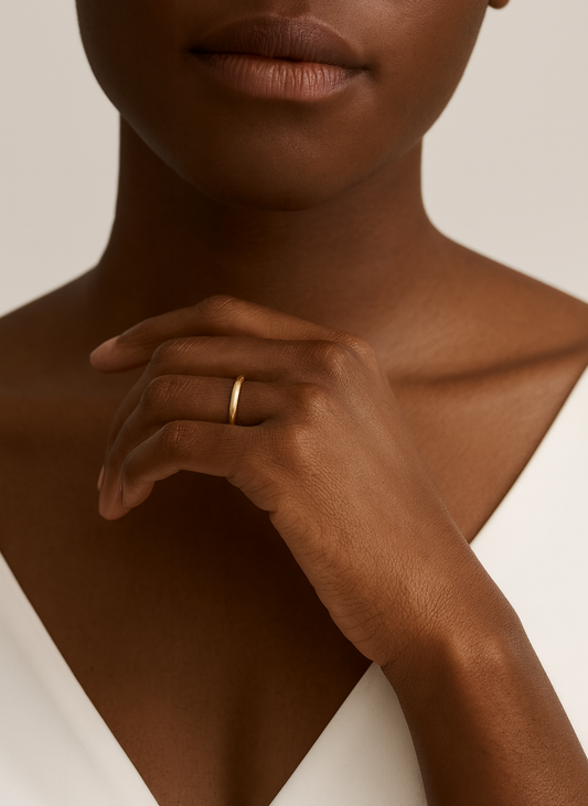 Close-up of a person wearing a gold ring on a neutral background