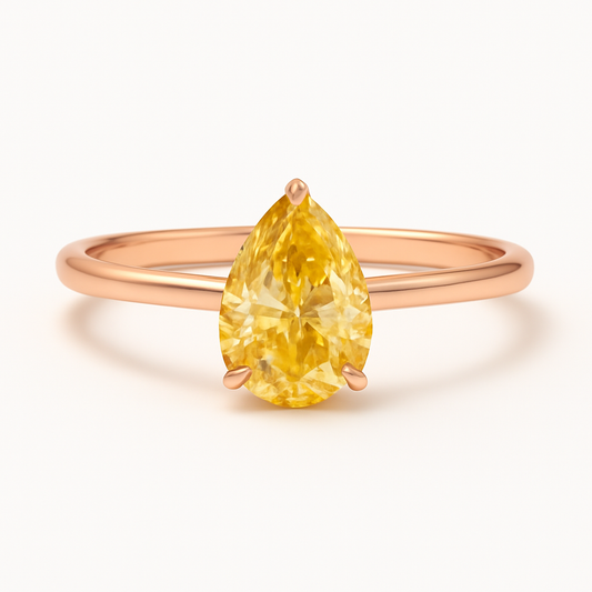 Rose gold ring with a yellow pear-shaped gemstone on a white background