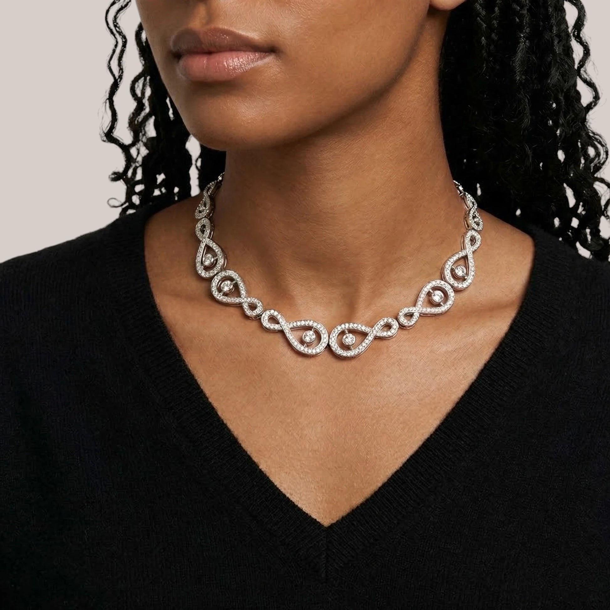 Woman wearing a silver necklace with a plain background