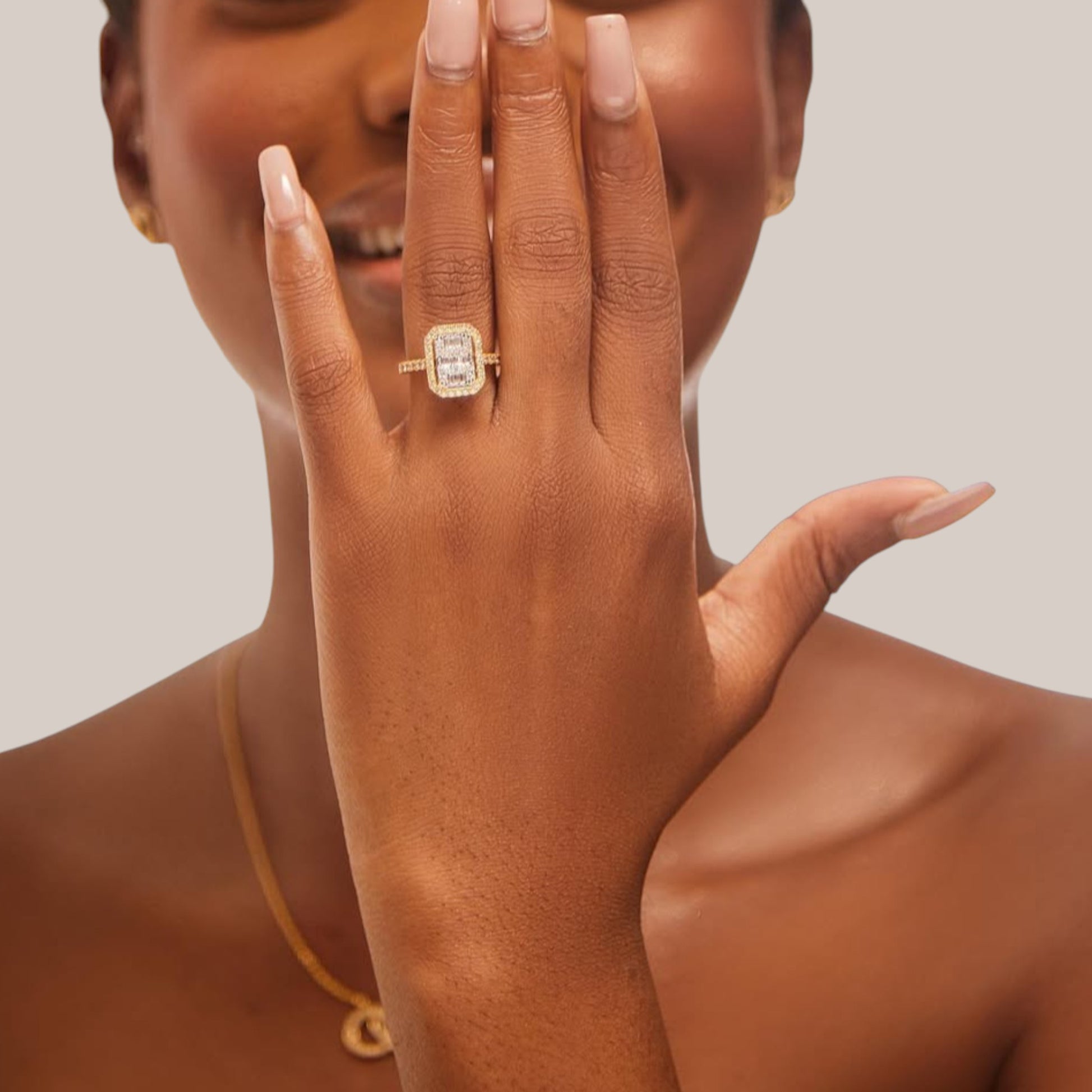 Close-up of a hand wearing a gold ring with a diamond on a neutral background