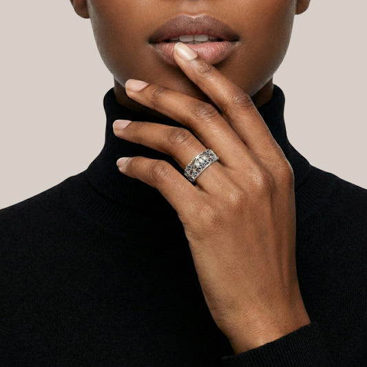 Close-up of a person wearing a black turtleneck and a ring on a neutral background