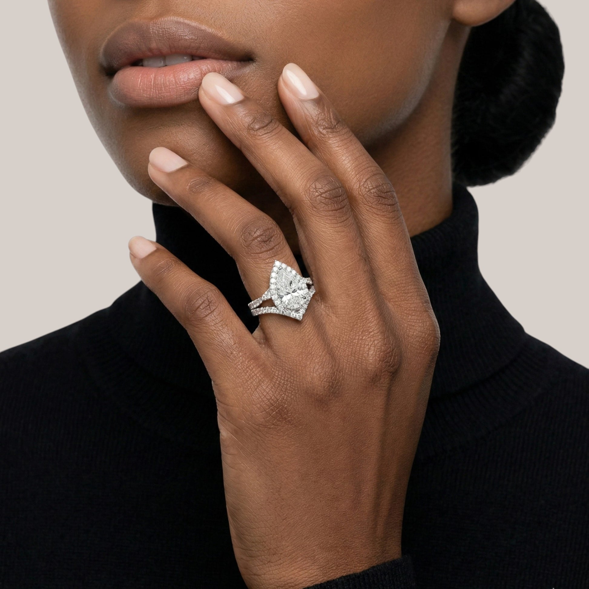Close-up of a hand wearing a diamond ring with a neutral background