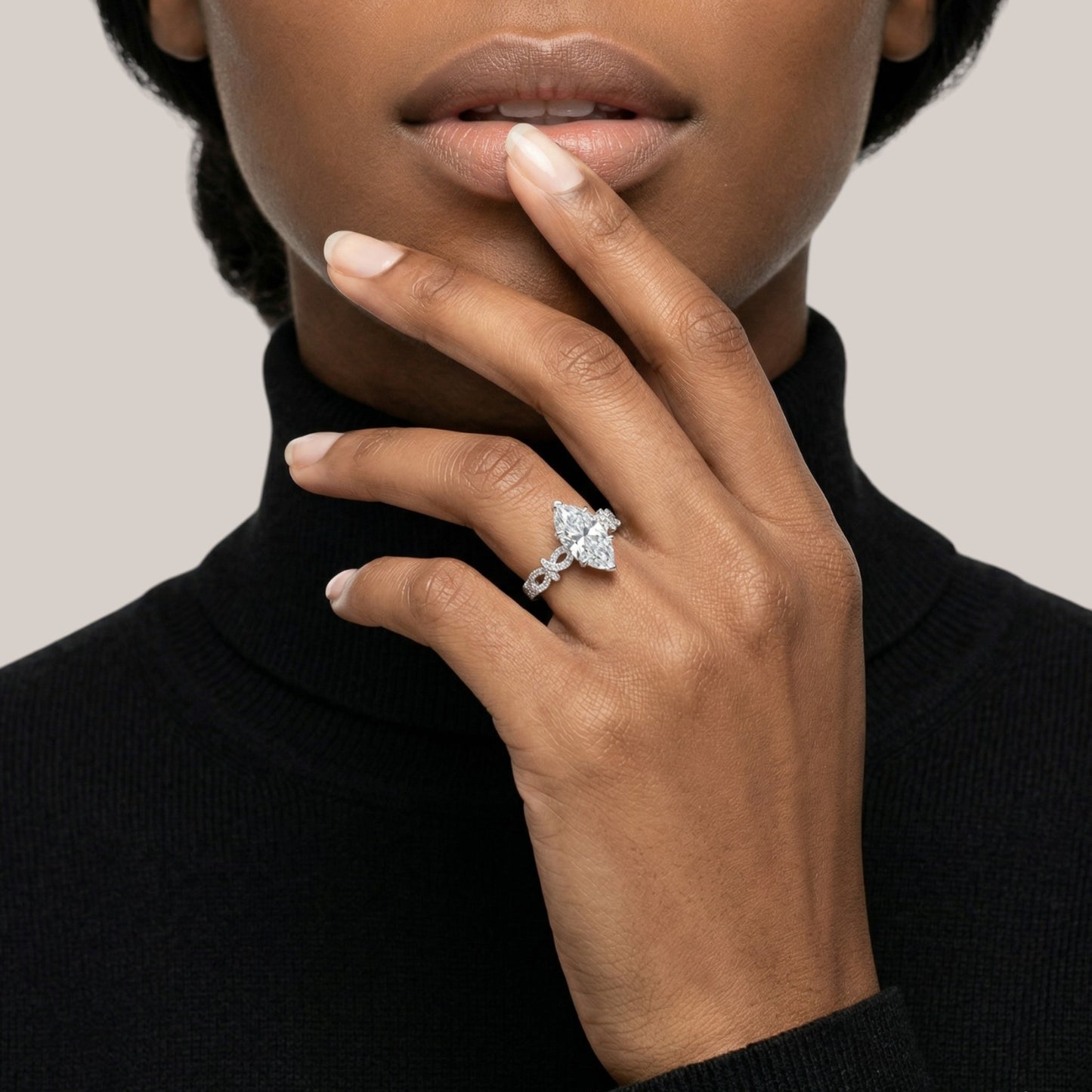 Close-up of a hand wearing a diamond ring with a neutral background