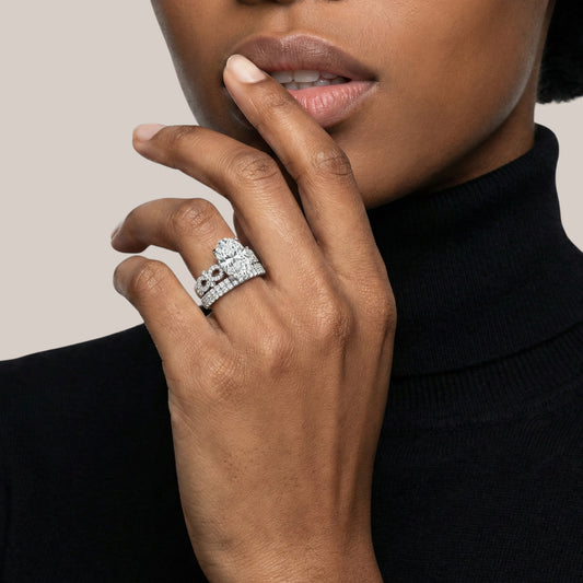 Close-up of a hand wearing a diamond ring with a neutral background