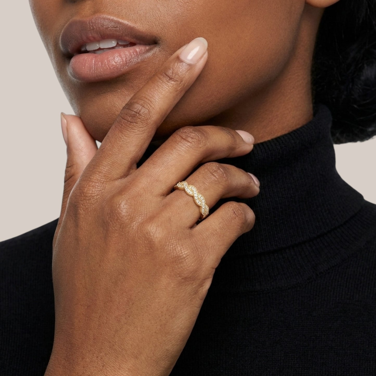 Close-up of a hand wearing a gold ring with a neutral background