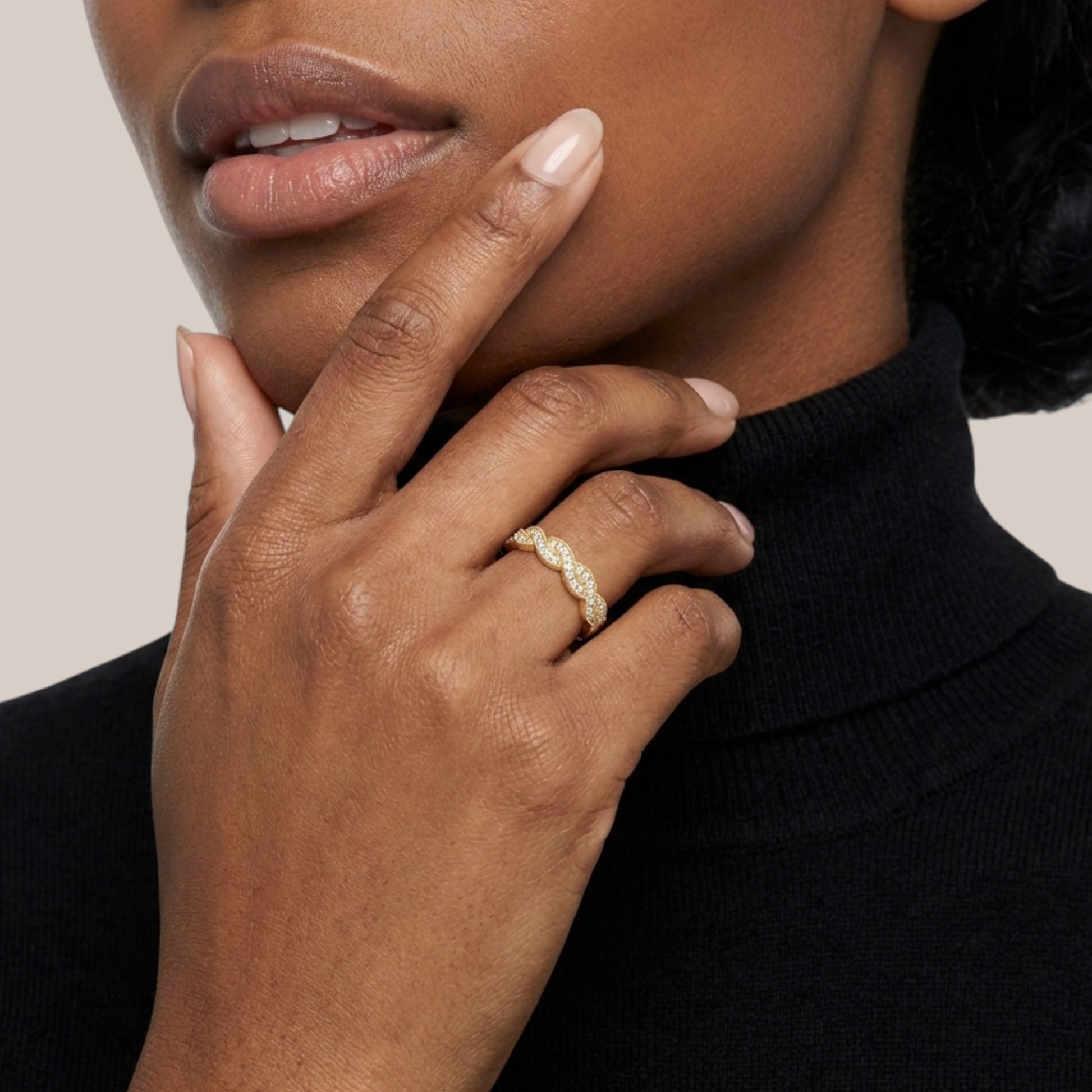 Close-up of a hand wearing a gold ring with a neutral background