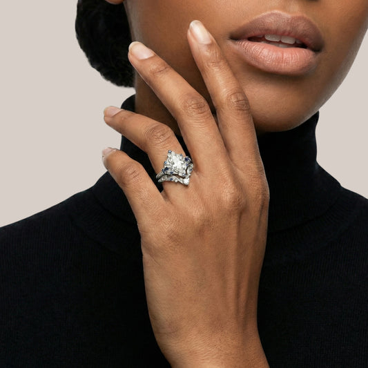 Close-up of a hand wearing a diamond ring with a neutral background
