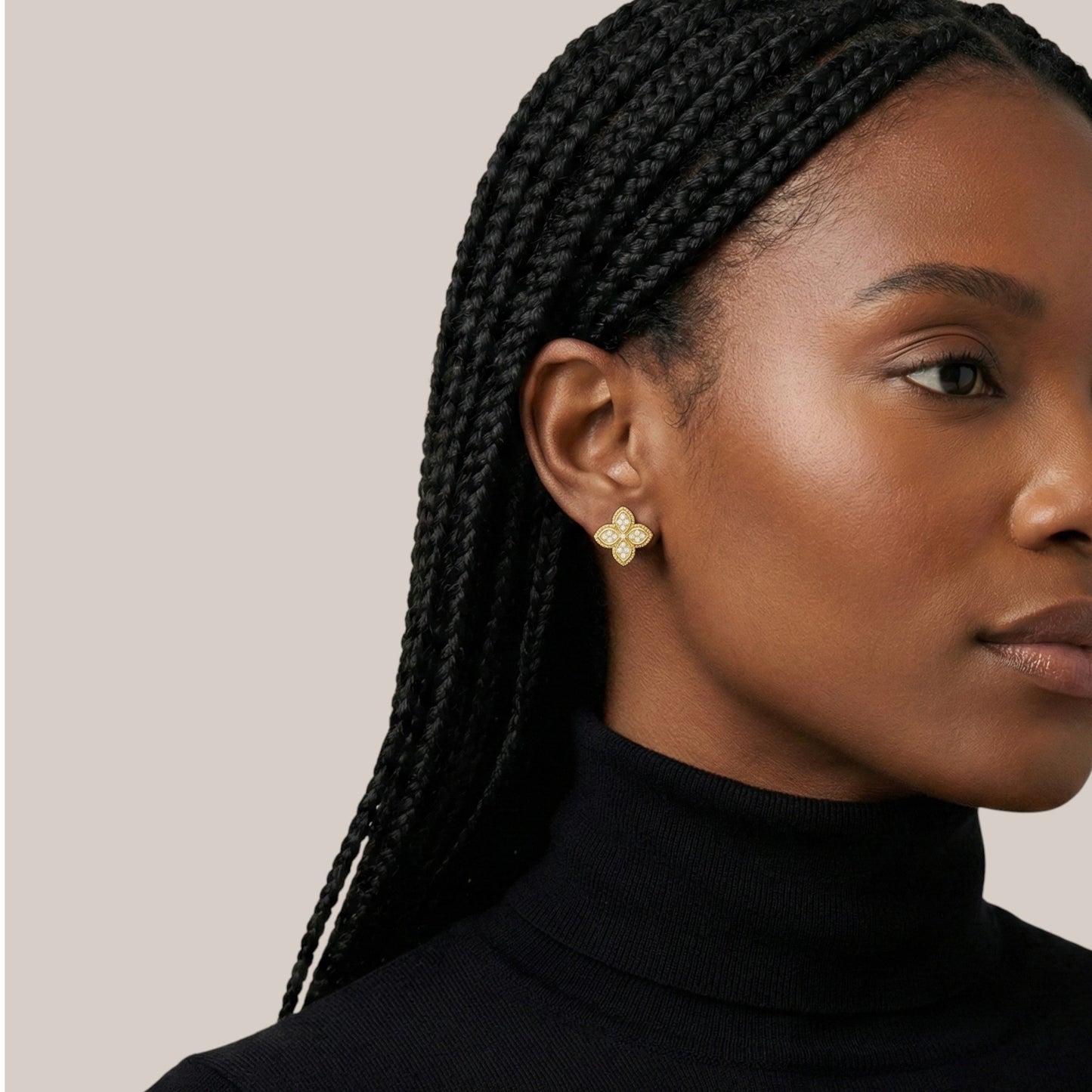 Woman wearing gold earrings with a neutral background