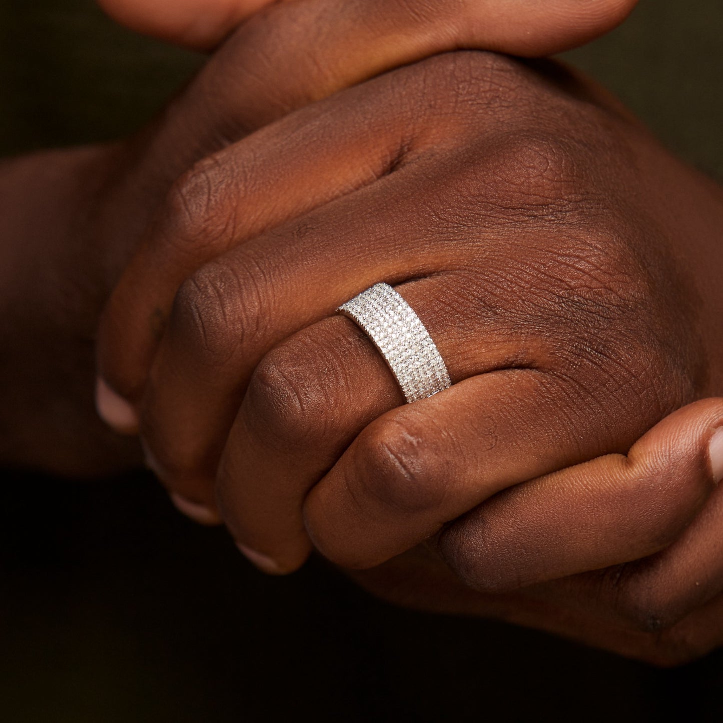 Close-up of a hand wearing a silver ring with a dark background