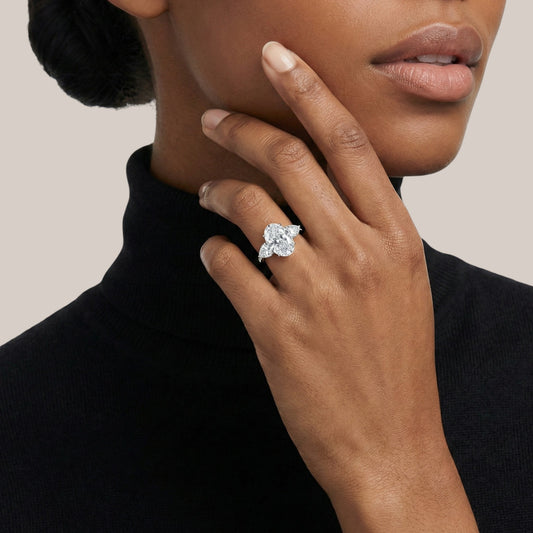 Close-up of a hand wearing a diamond ring with a neutral background
