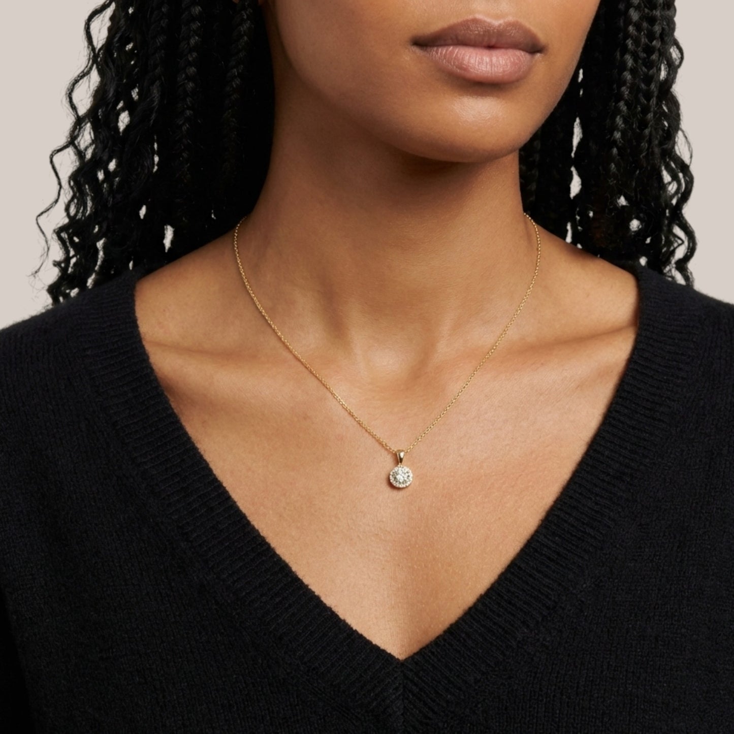 Woman wearing a gold necklace with a pendant against a neutral background