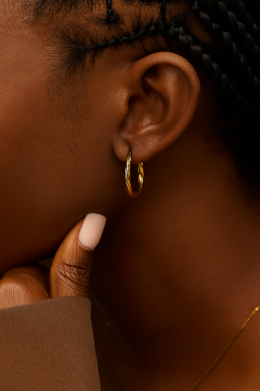 Close-up of an ear wearing a gold hoop earring with a blurred background