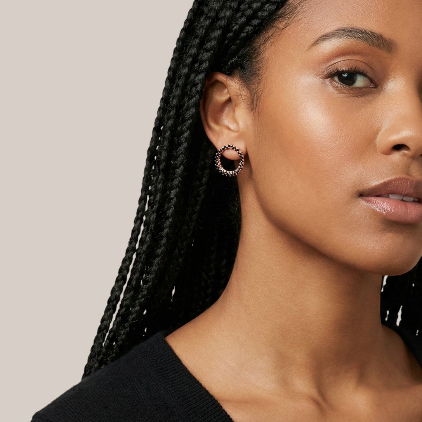 Close-up of a woman wearing a black hoop earring against a neutral background
