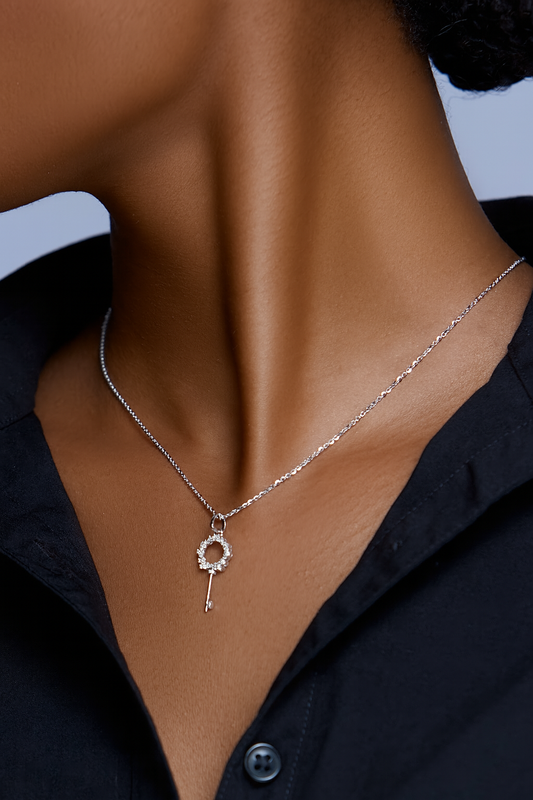 Necklace with a key pendant worn by a person against a neutral background
