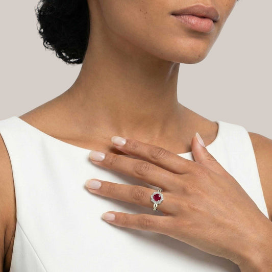 Woman wearing a red gemstone ring on a plain background