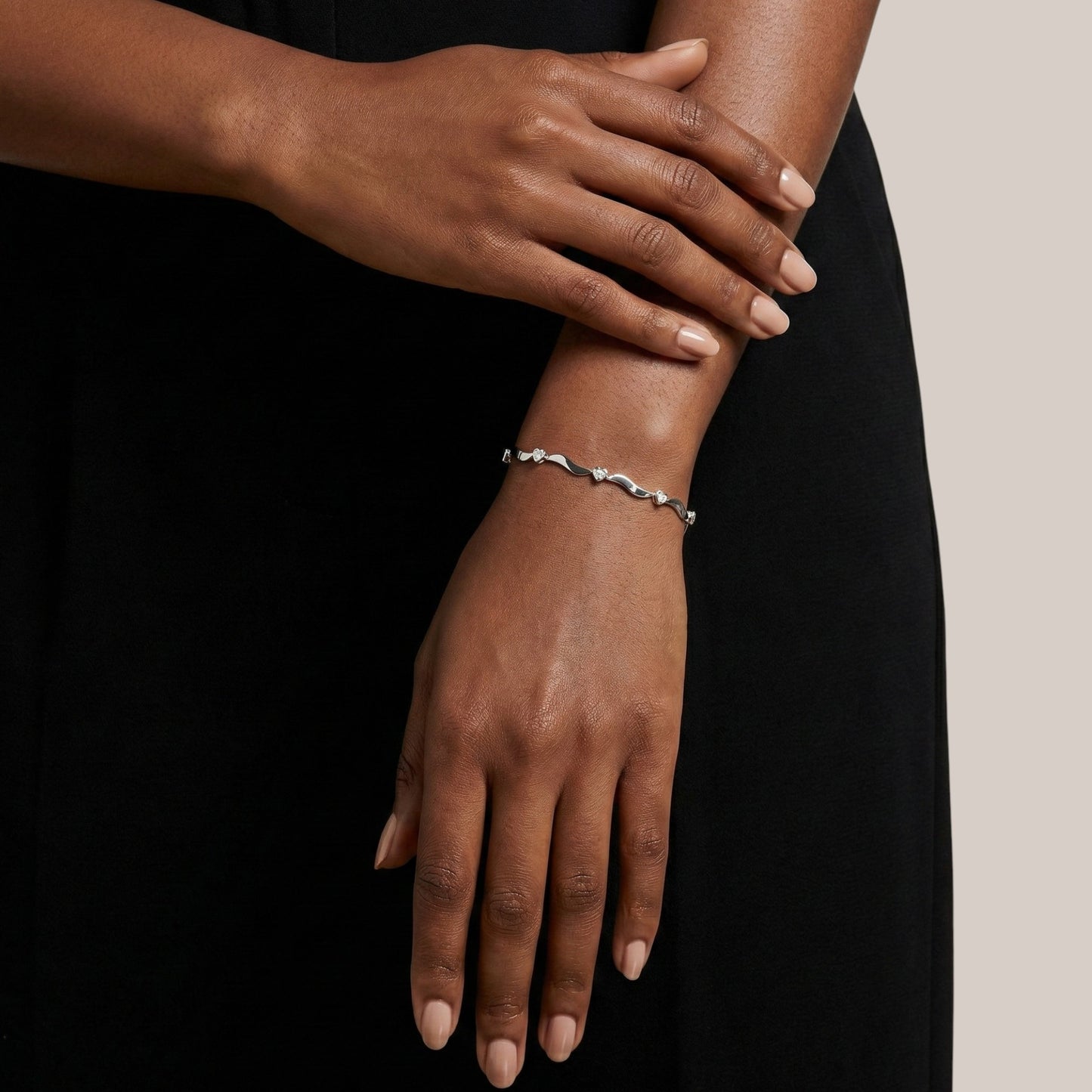 Close-up of a person's wrist wearing a silver bracelet against a black background