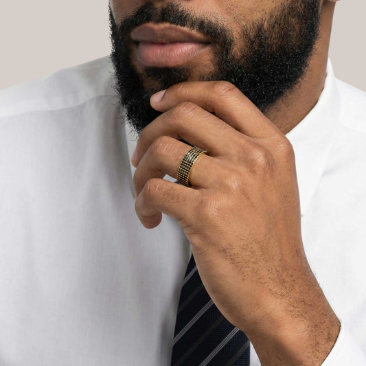 Man wearing a white shirt and striped tie with a gold ring on his finger.