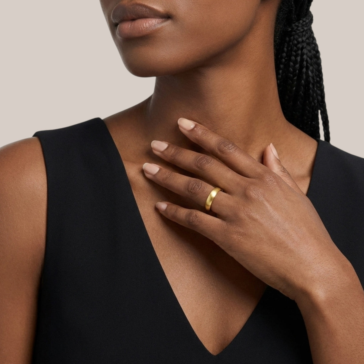 Woman wearing a gold ring on her hand with a neutral background