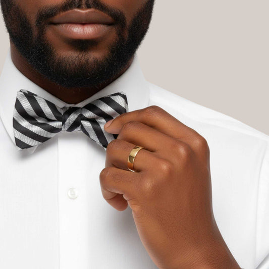 Man adjusting a black and white striped bow tie with a neutral background