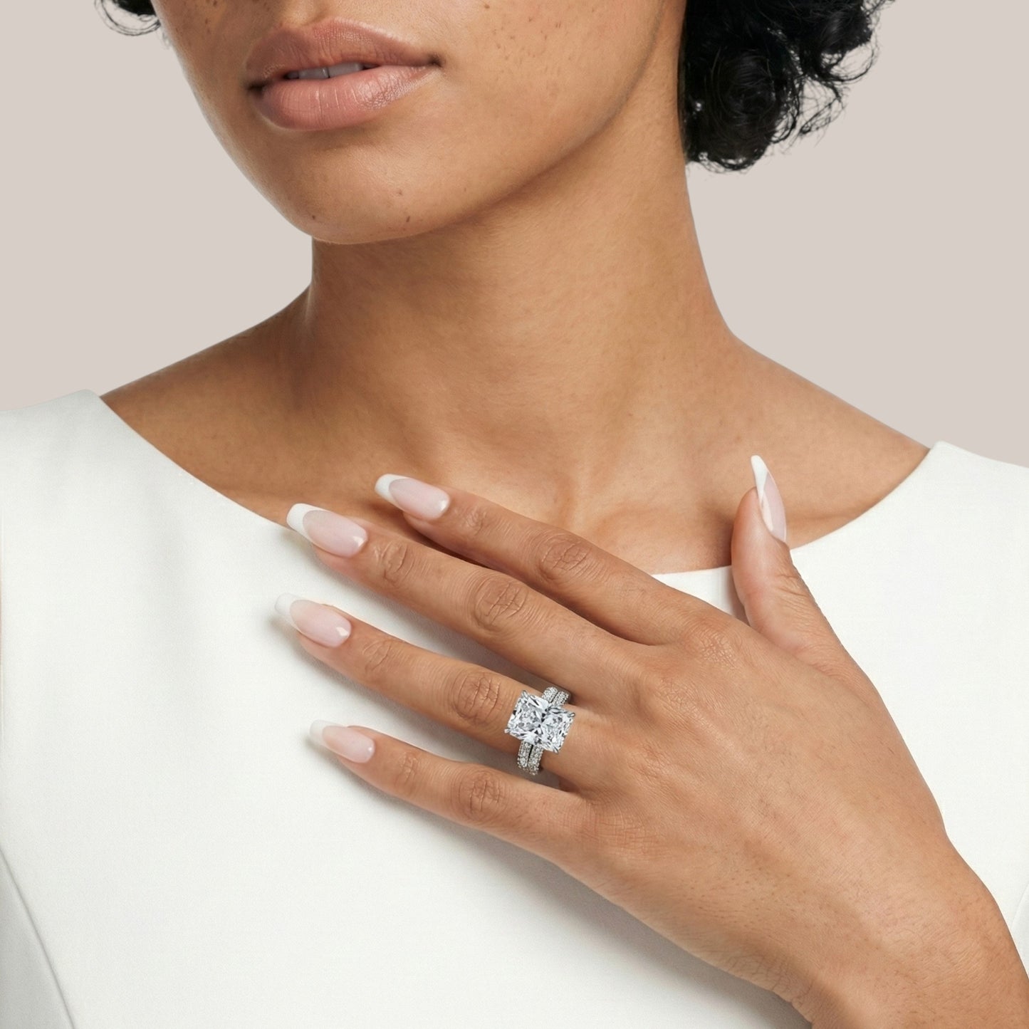 Close-up of a woman's hand wearing a diamond ring on a plain background