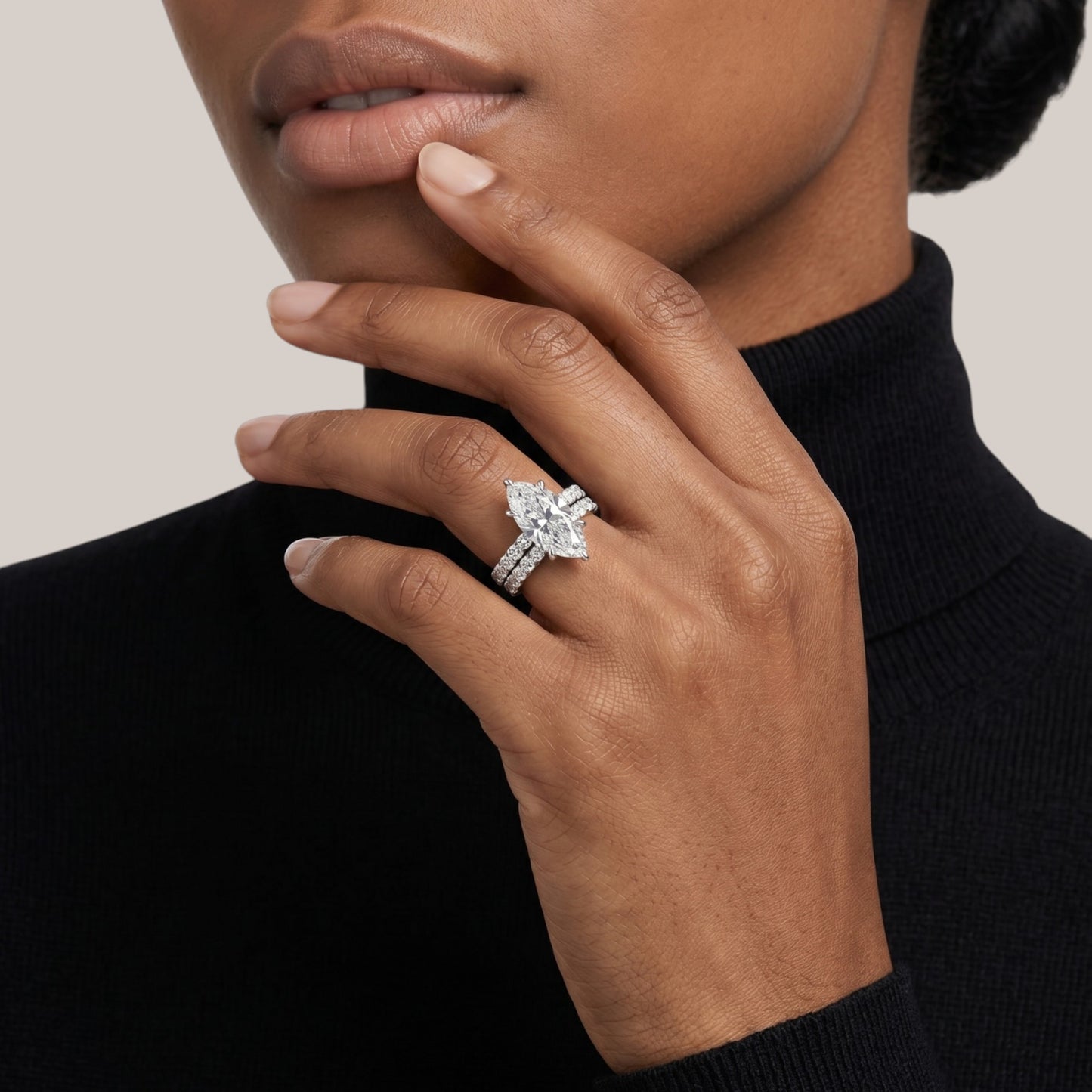 Close-up of a hand wearing a diamond ring with a neutral background