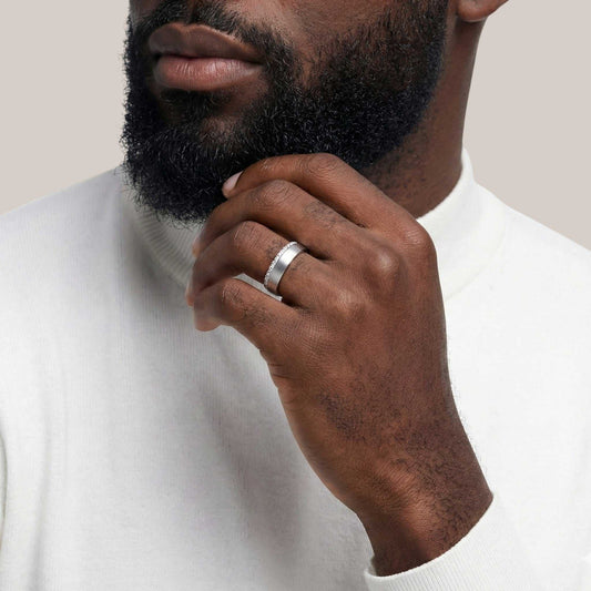 Man wearing a silver ring on his finger, with a neutral background