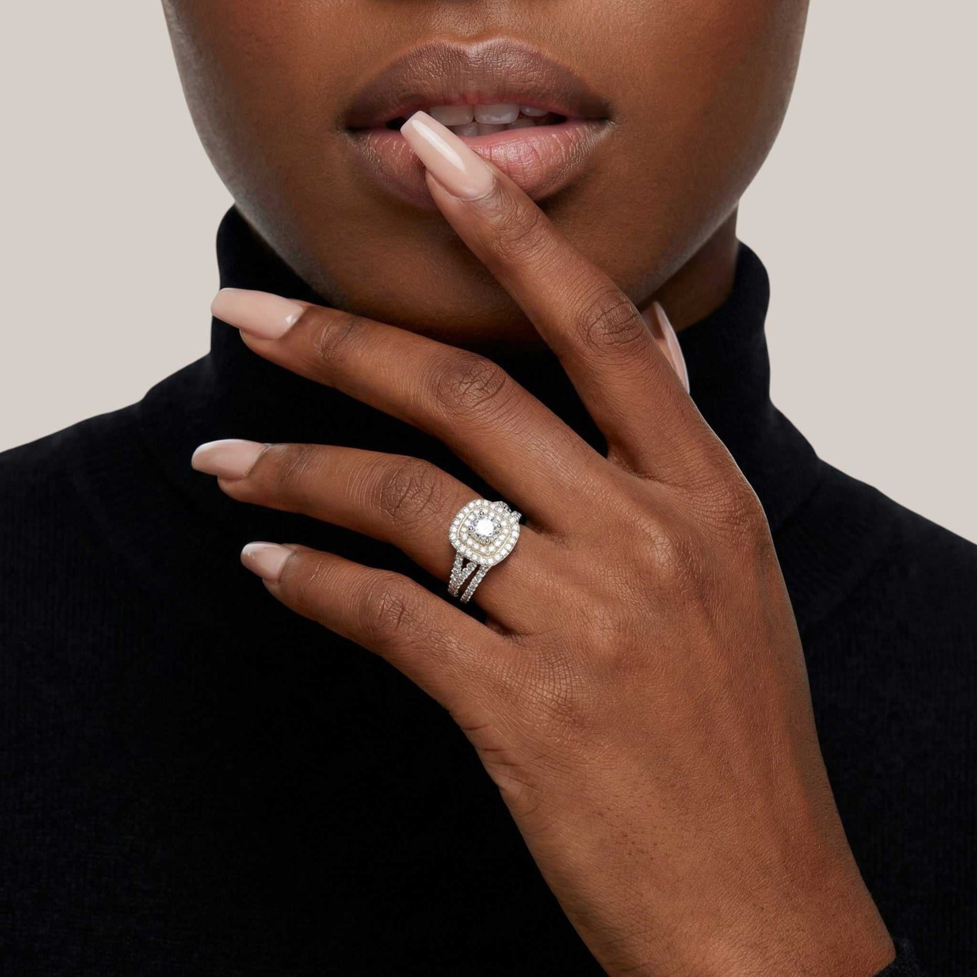 Close-up of a hand wearing a diamond ring with a neutral background