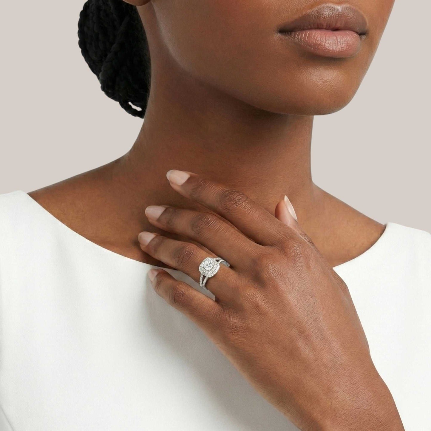 Close-up of a woman wearing a silver ring with a diamond on a plain background