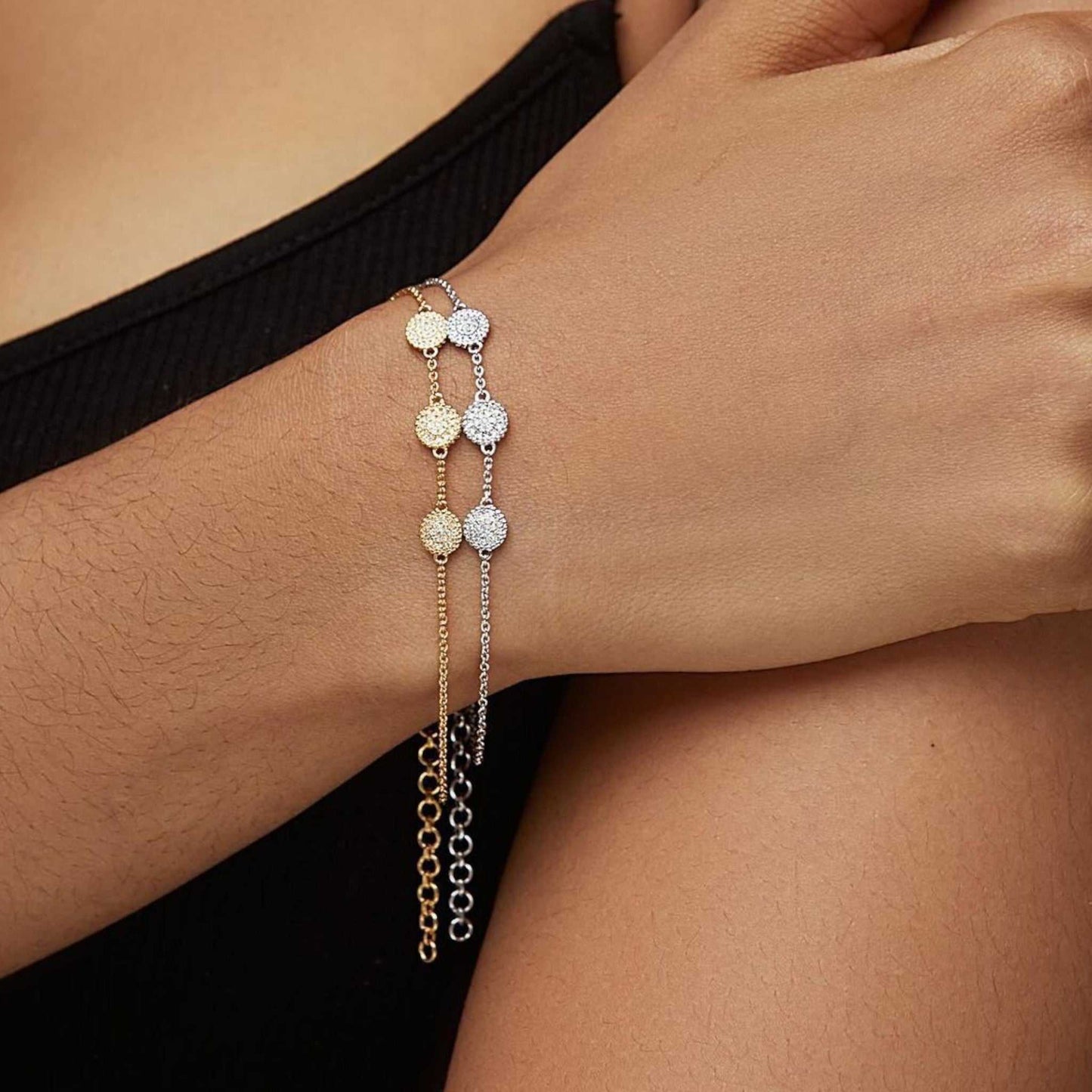 Close-up of a person's wrist wearing a delicate bracelet with gold and silver charms.