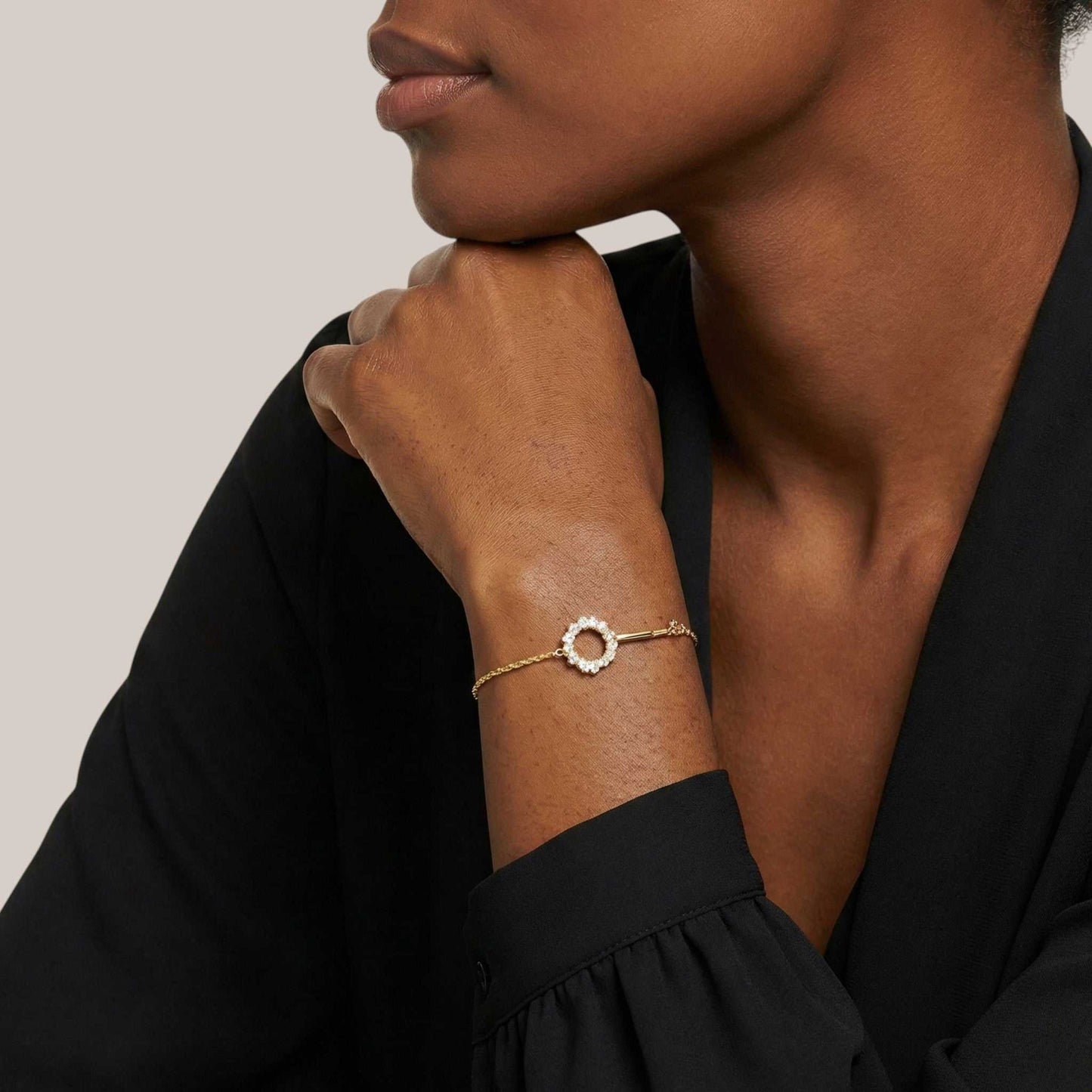 Woman wearing a gold bracelet on a neutral background