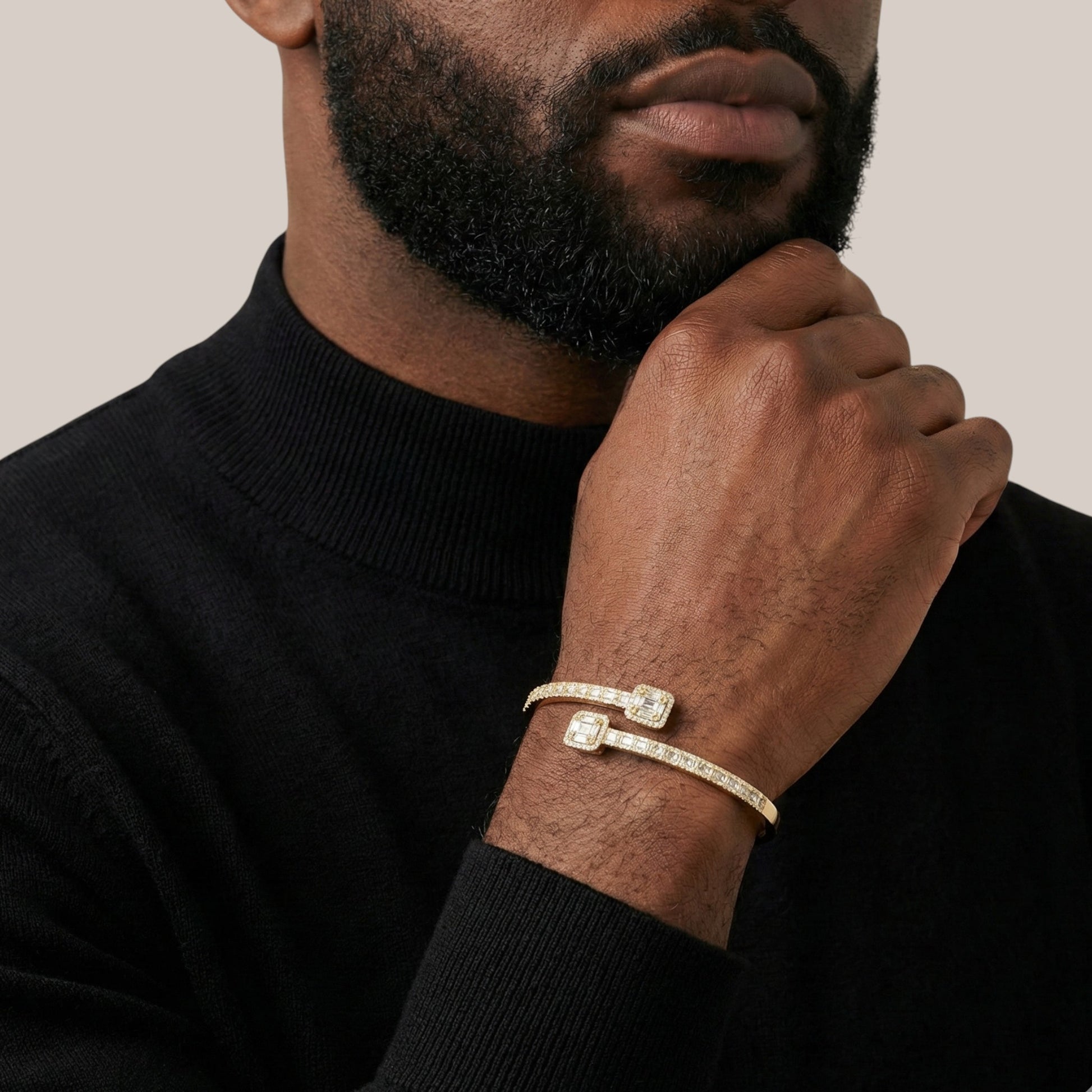 Man wearing a gold bracelet on his wrist with a neutral background