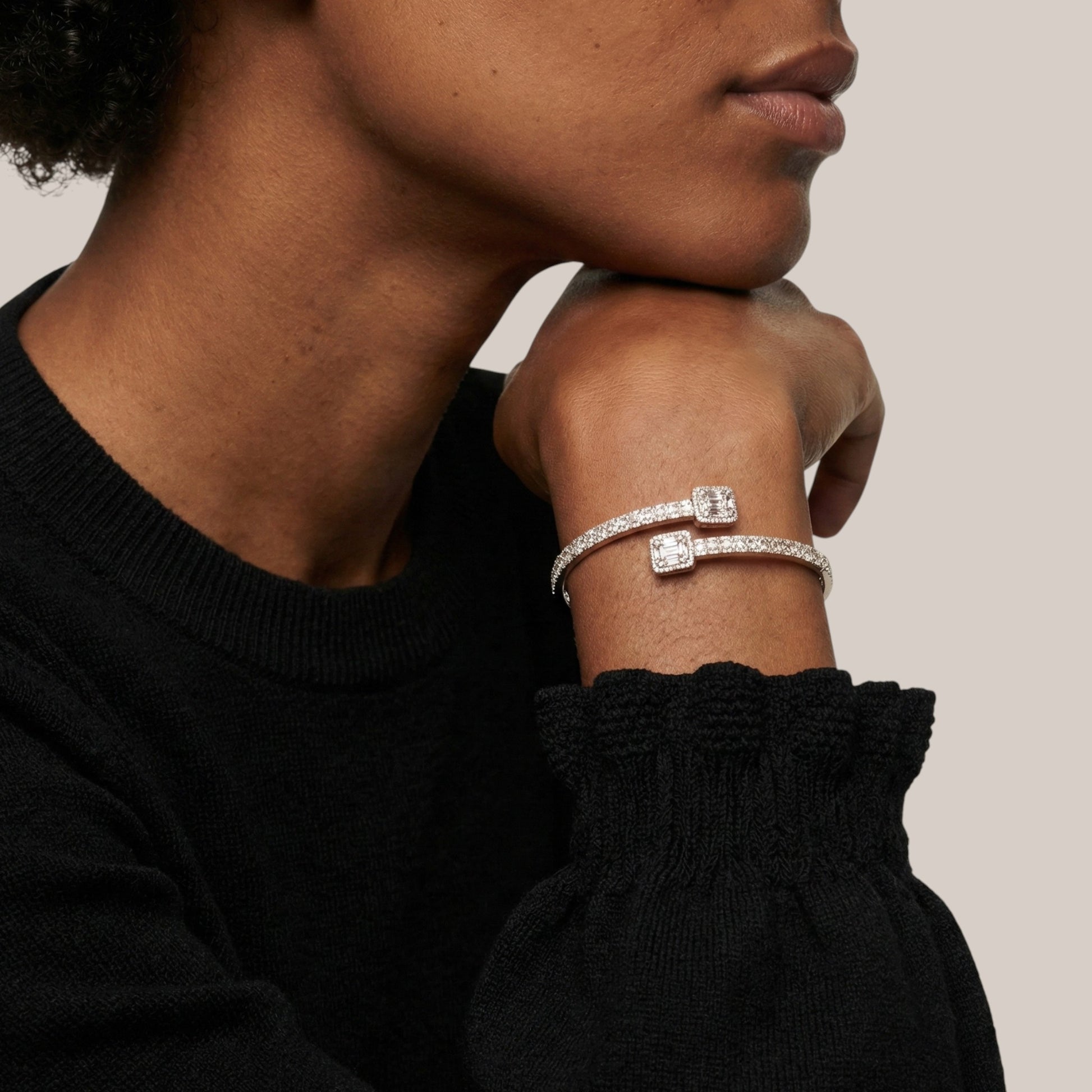 Person wearing a silver bracelet with clear stones on a neutral background