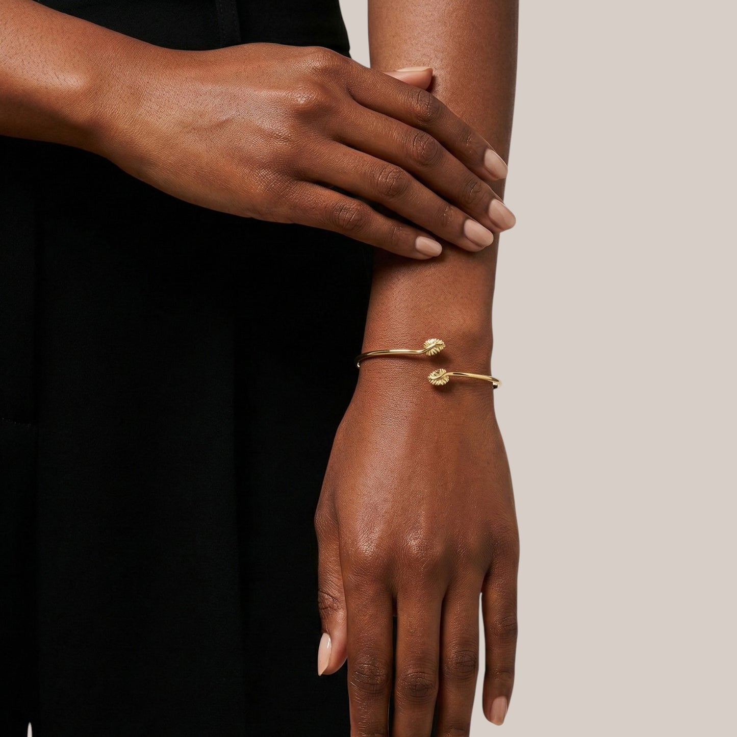 Gold bracelet on a wrist with a neutral background
