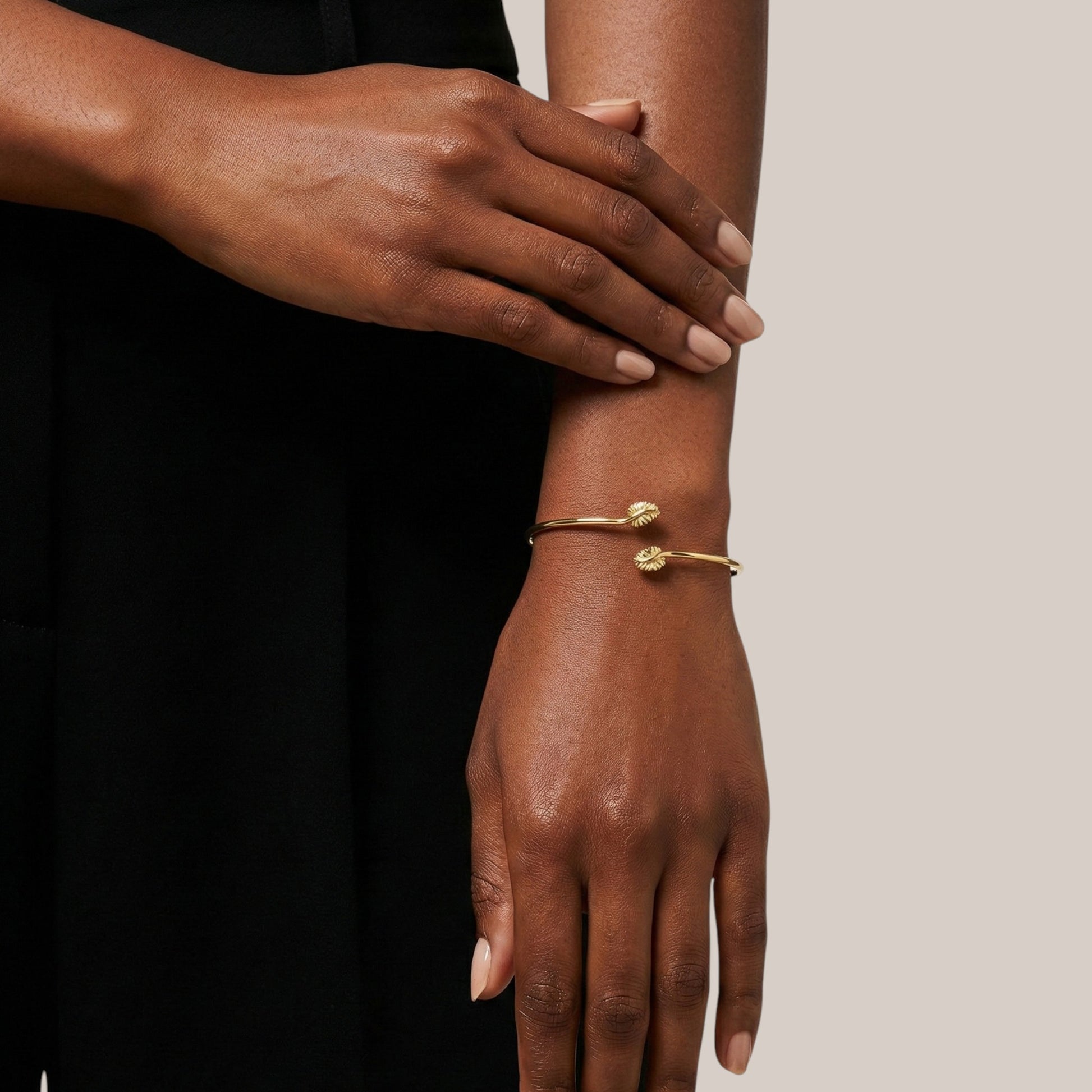 Gold bracelet on a wrist with a neutral background