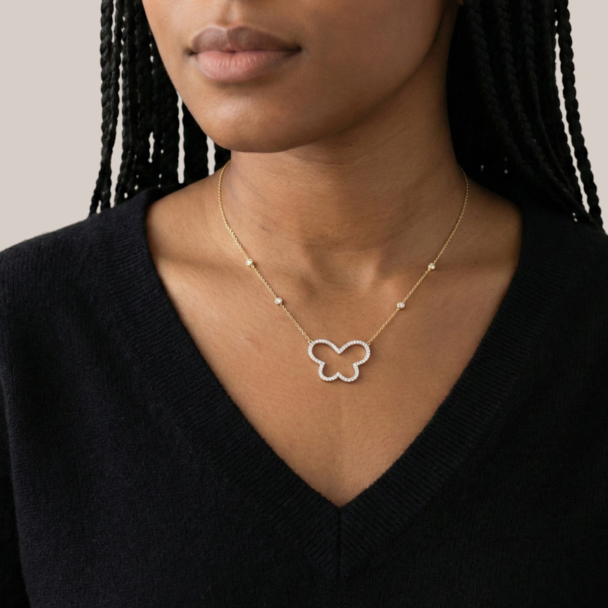 Necklace with a butterfly pendant worn by a person against a neutral background