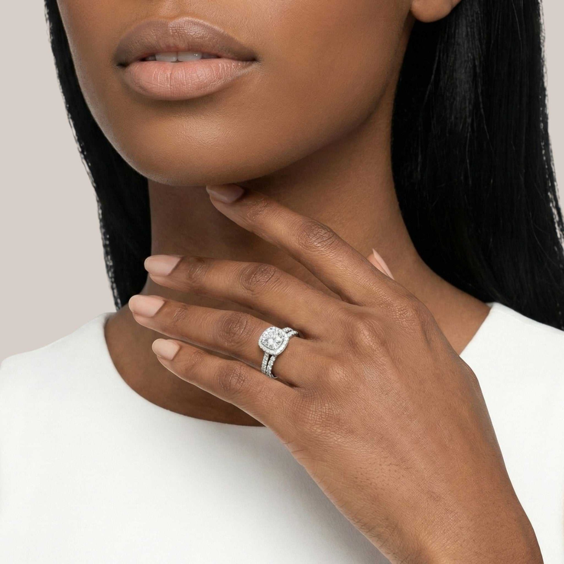 Close-up of a woman's hand wearing a diamond ring on a neutral background