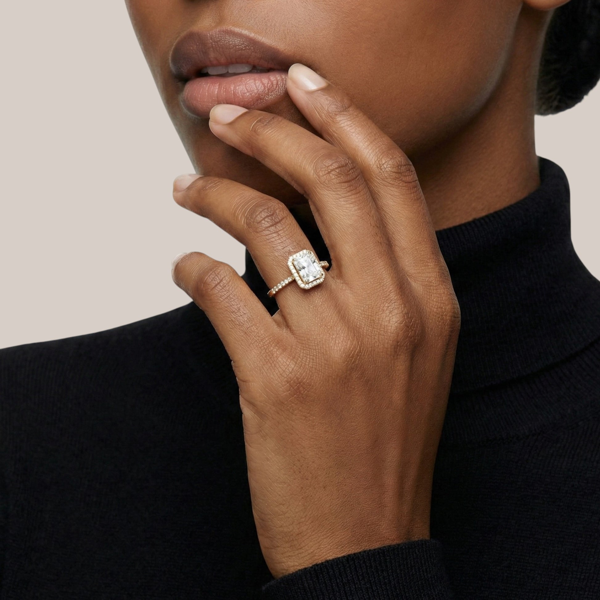 Hand wearing a diamond ring with a neutral background