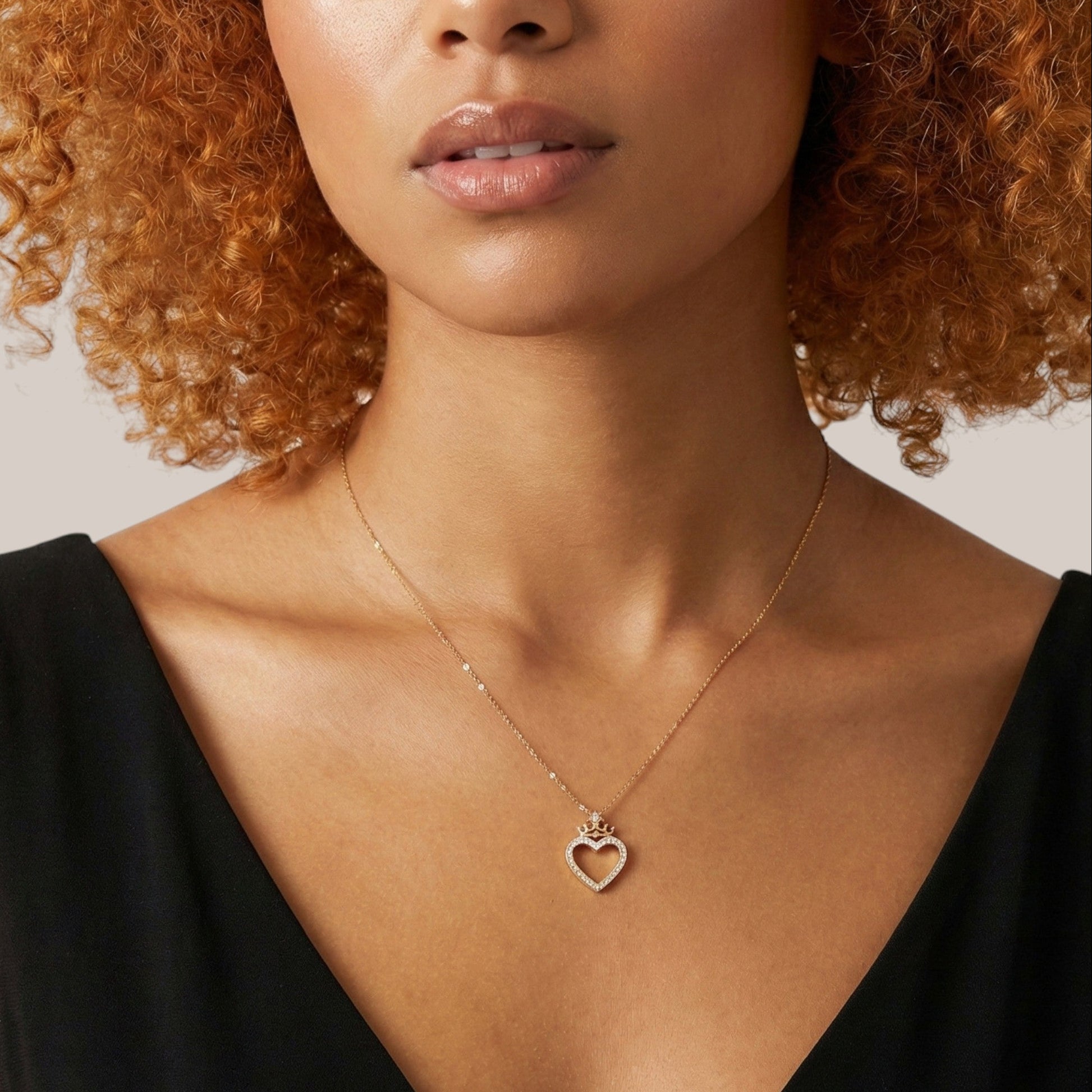 Woman wearing a gold necklace with a heart pendant against a neutral background