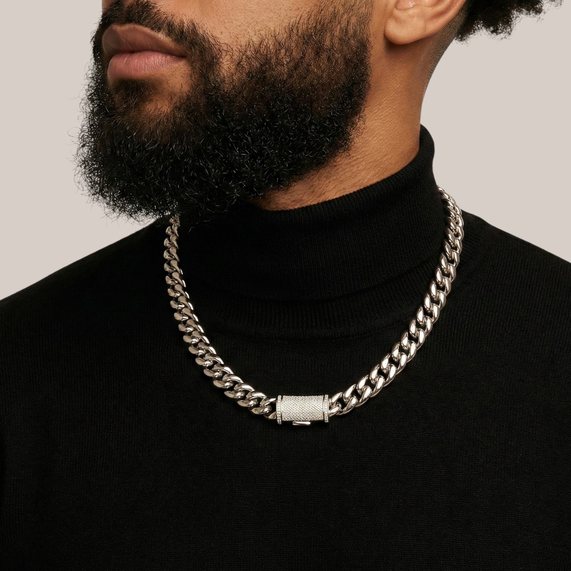 Man wearing a black turtleneck and silver chain necklace on a plain background