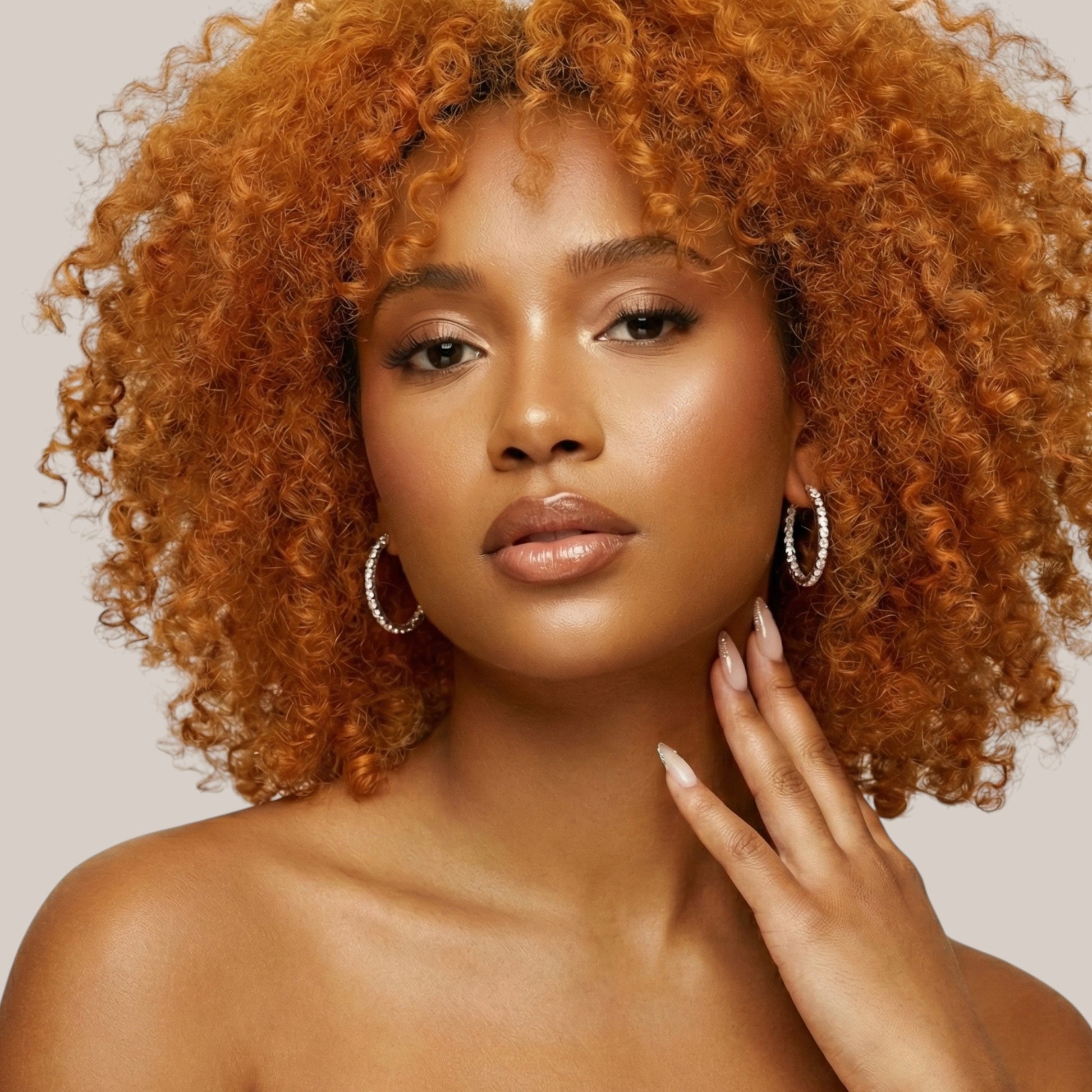 Woman with curly hair posing against a neutral background