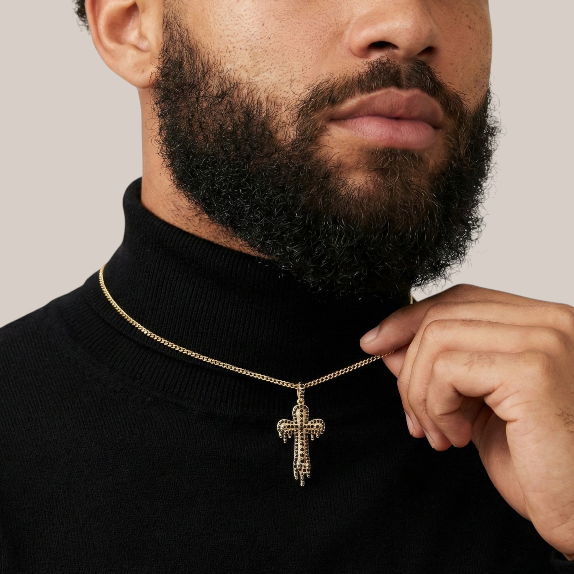 Man wearing a black turtleneck and gold necklace with a cross pendant.