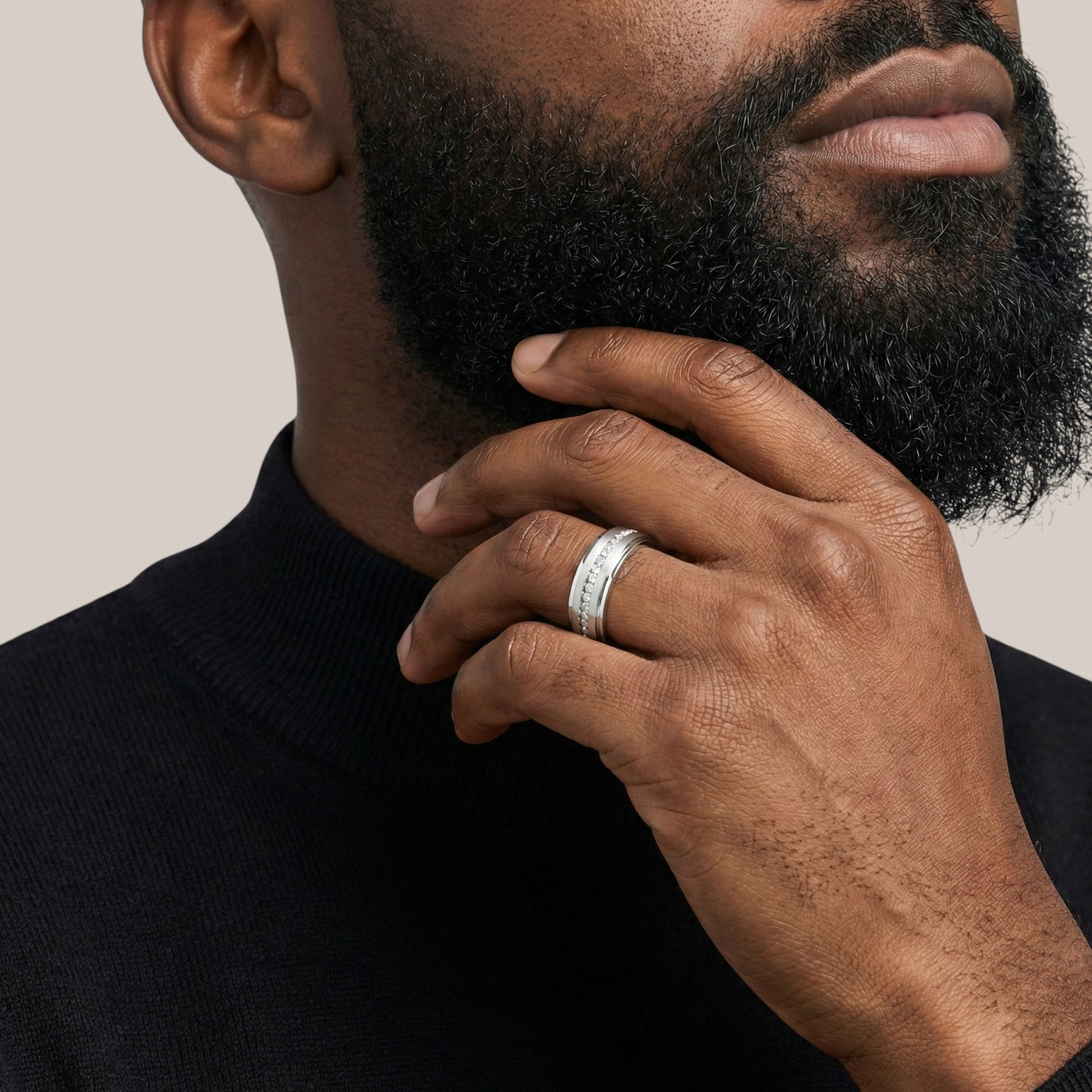 Man wearing a silver ring on his hand with a neutral background