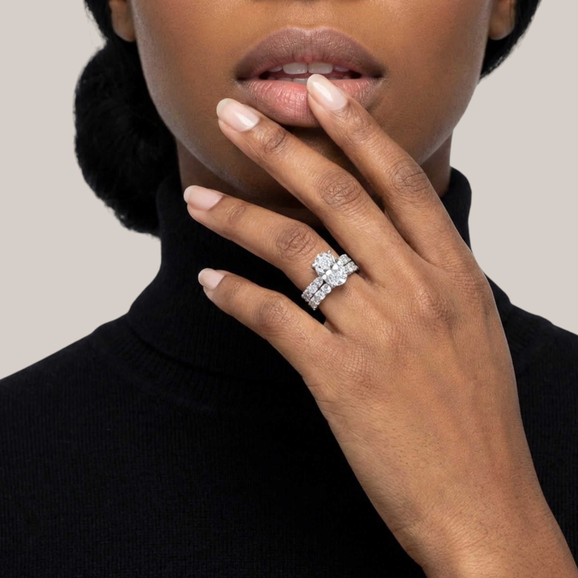 Close-up of a hand wearing a diamond ring with a neutral background