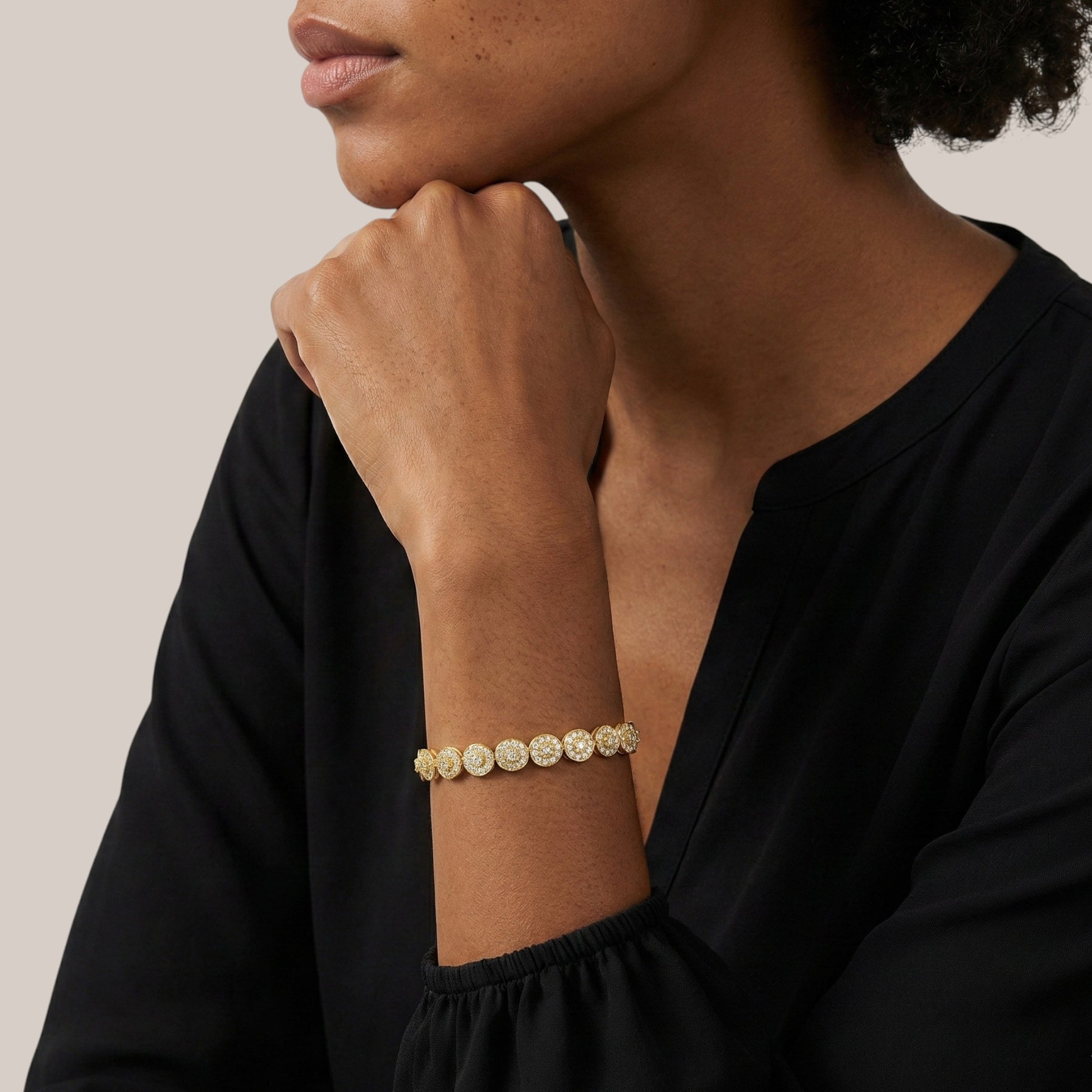 Woman wearing a gold bracelet on a neutral background