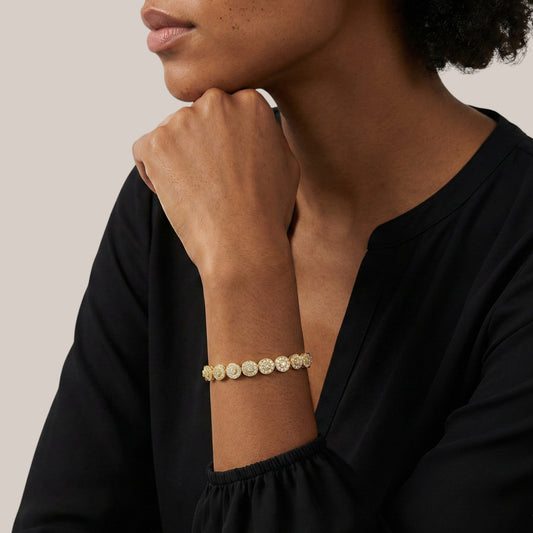 Woman wearing a gold bracelet on a neutral background