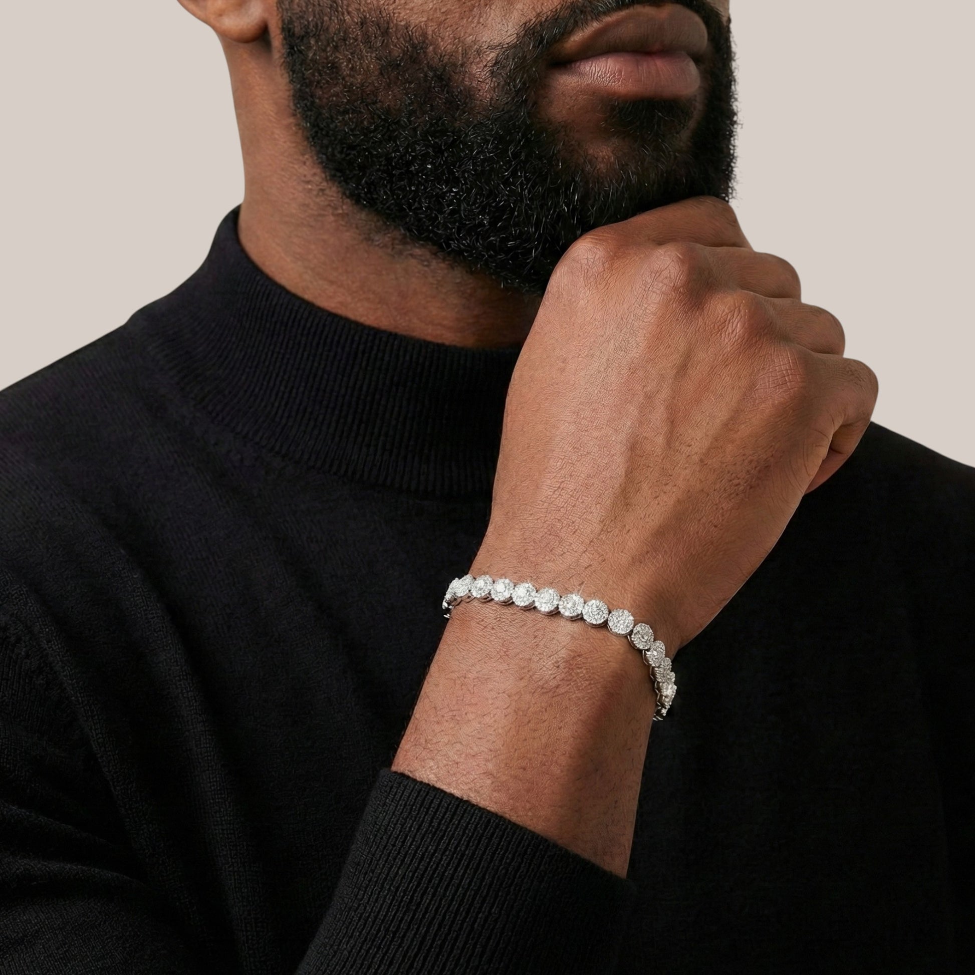 Man wearing a black turtleneck and diamond bracelet on a neutral background
