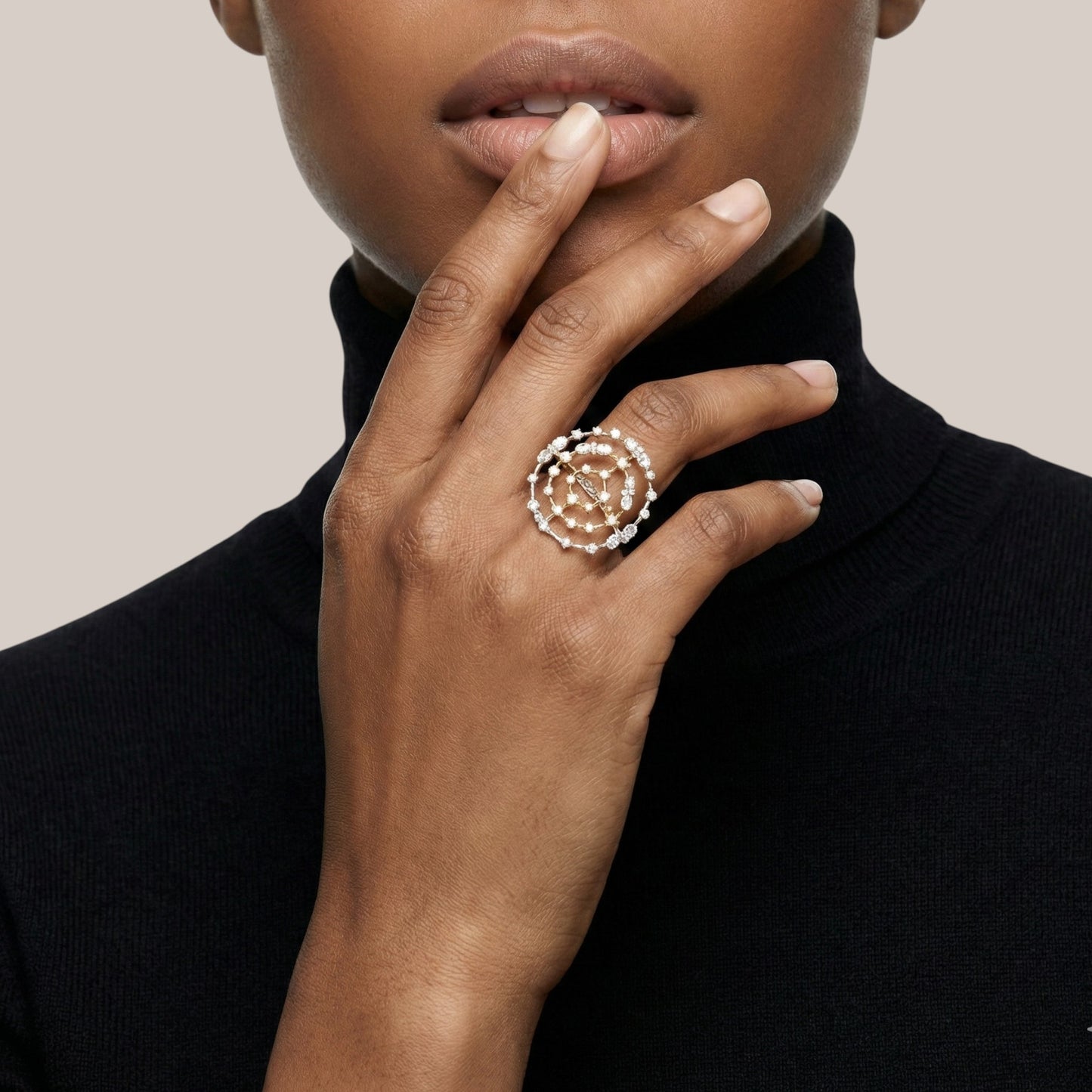Close-up of a hand wearing a decorative ring with a neutral background