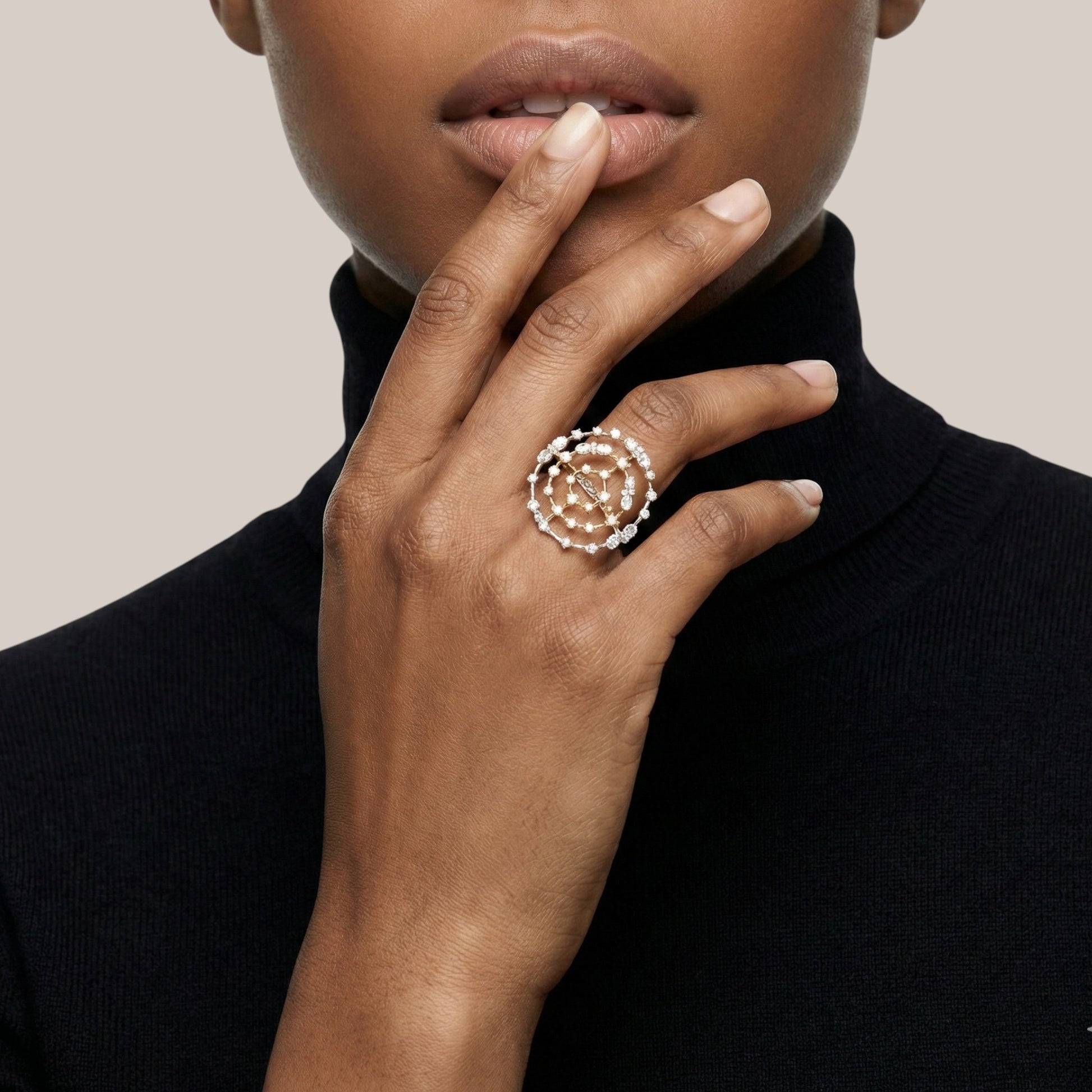Close-up of a hand wearing a decorative ring with a neutral background